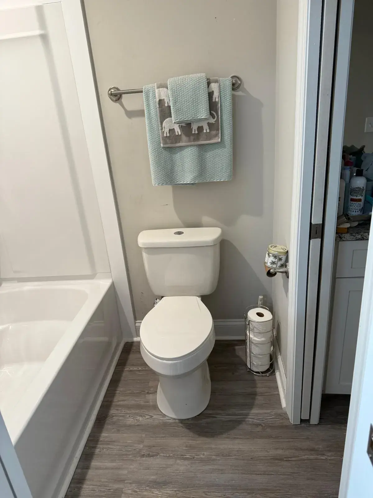 Toilet and new gray vinyl floor beside a white tub