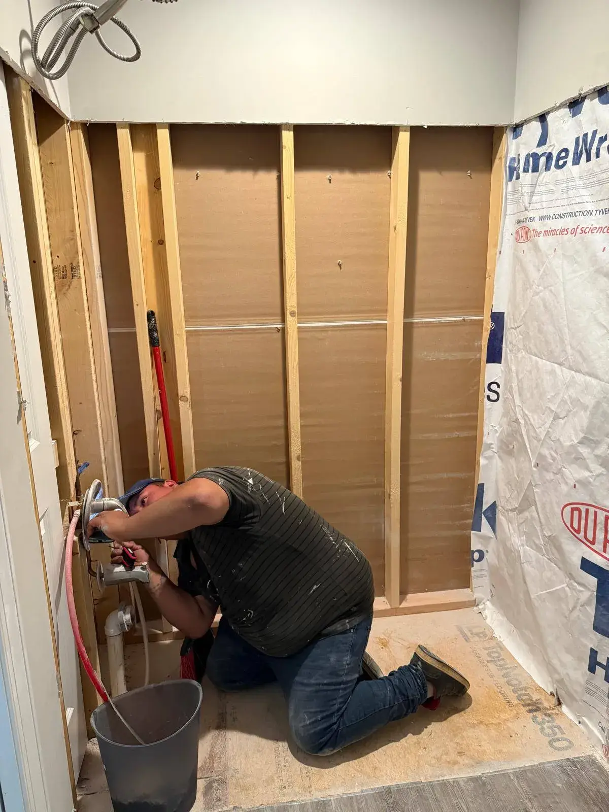 Kava crew member connecting plumbing in a bathroom opened to the studs