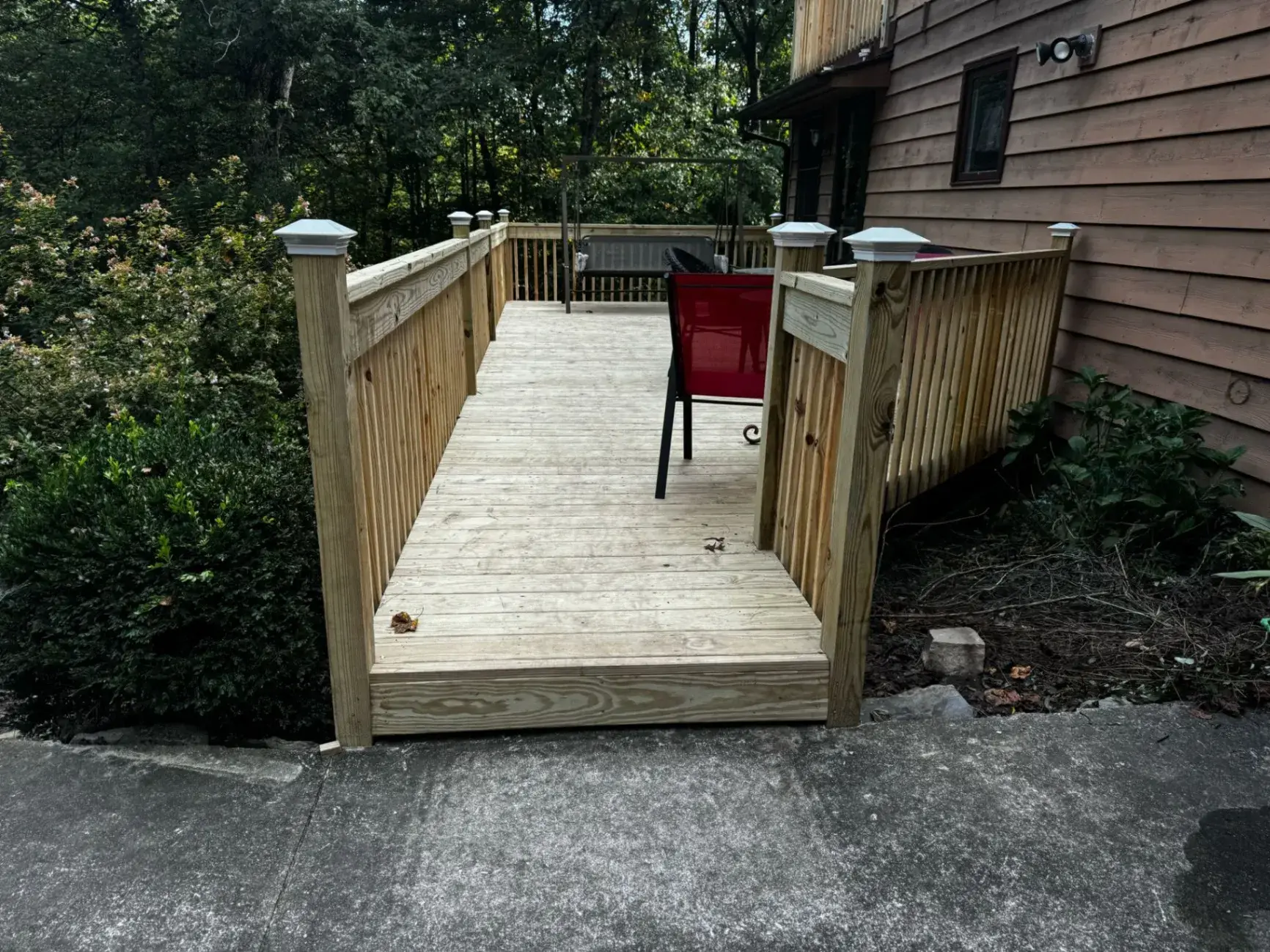 Long pressure-treated deck with capped posts and a red chair