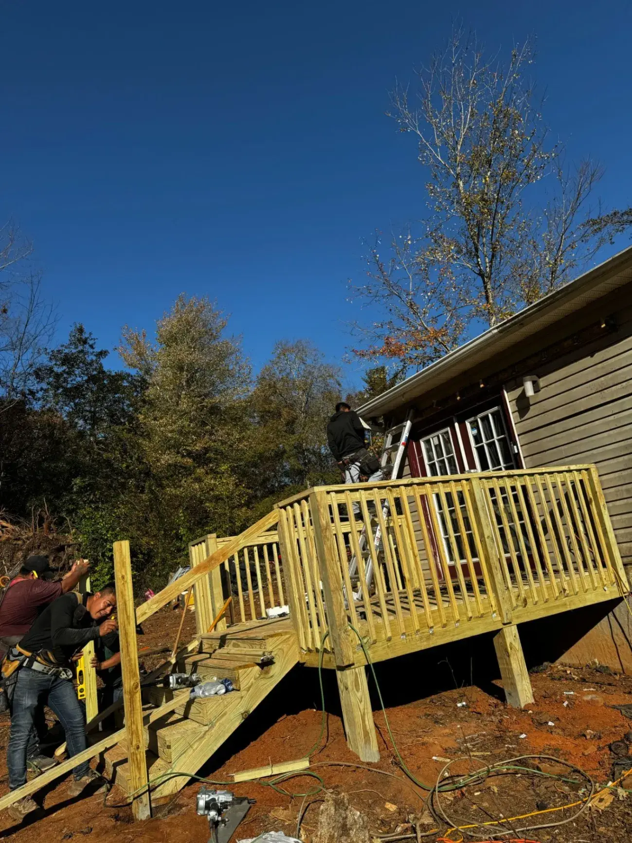 Crew finishing a deck and stairs under a blue sky