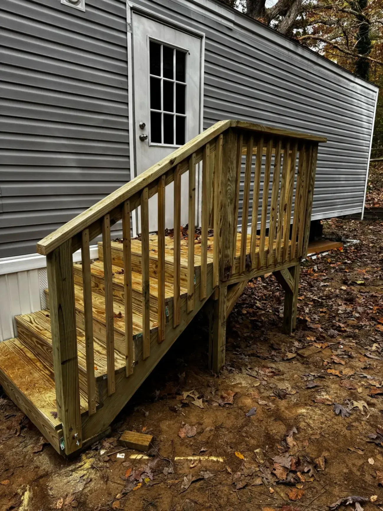 New deck with stairs on the side of a gray home