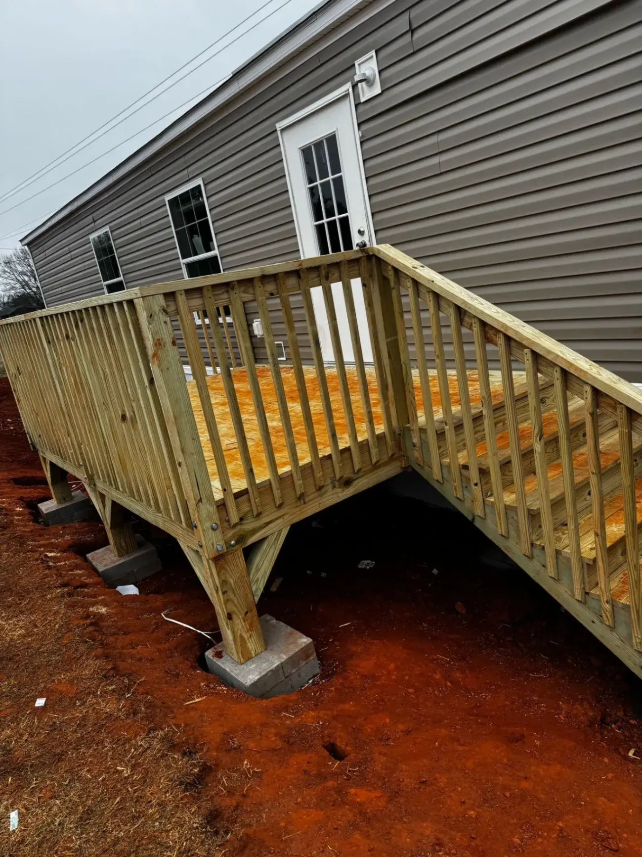 Deck and stairs built on post footings next to a gray home