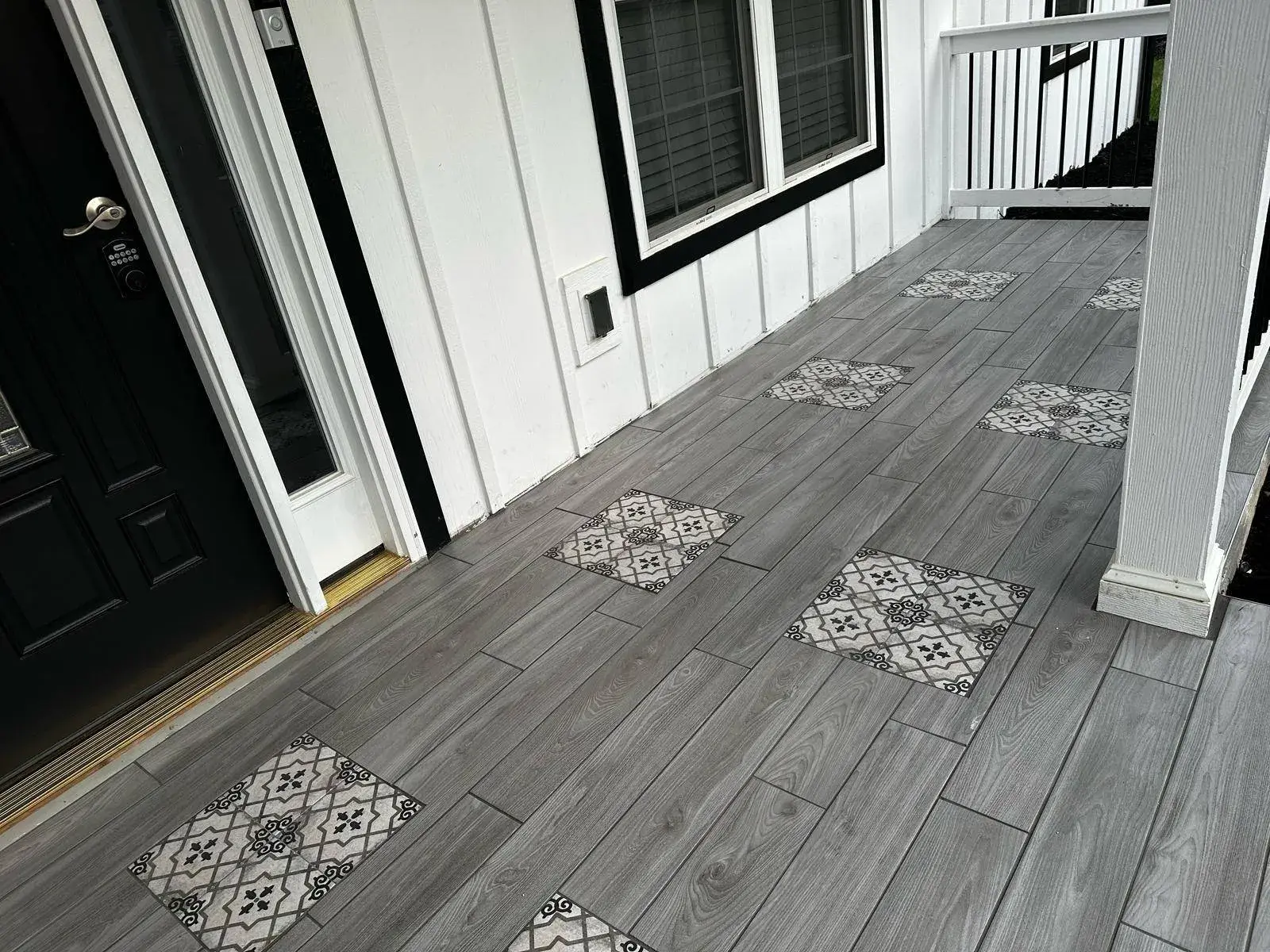 Porch tile with patterned inlays along a white board-and-batten wall