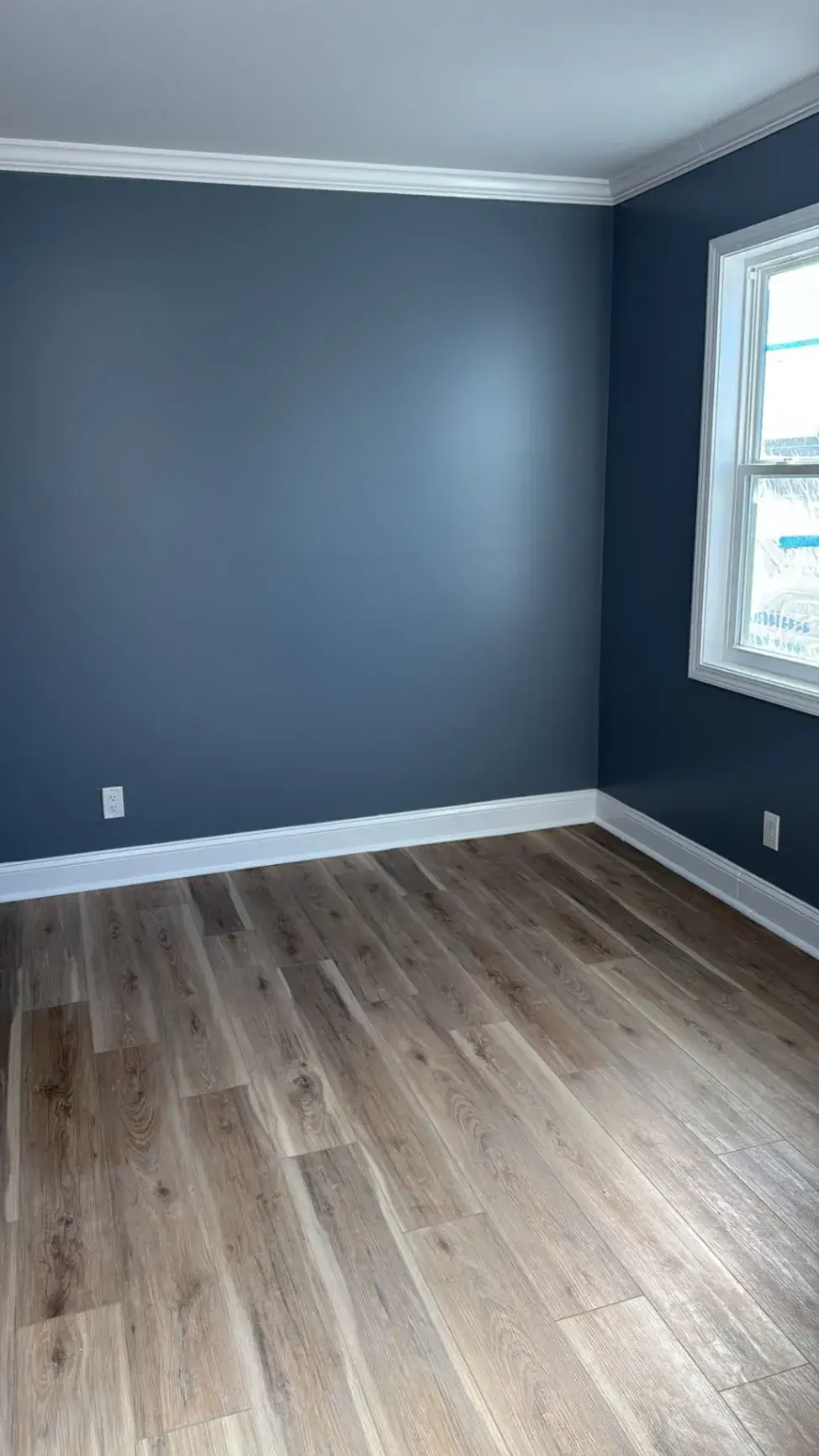 Plank floor and white baseboard in a blue painted room