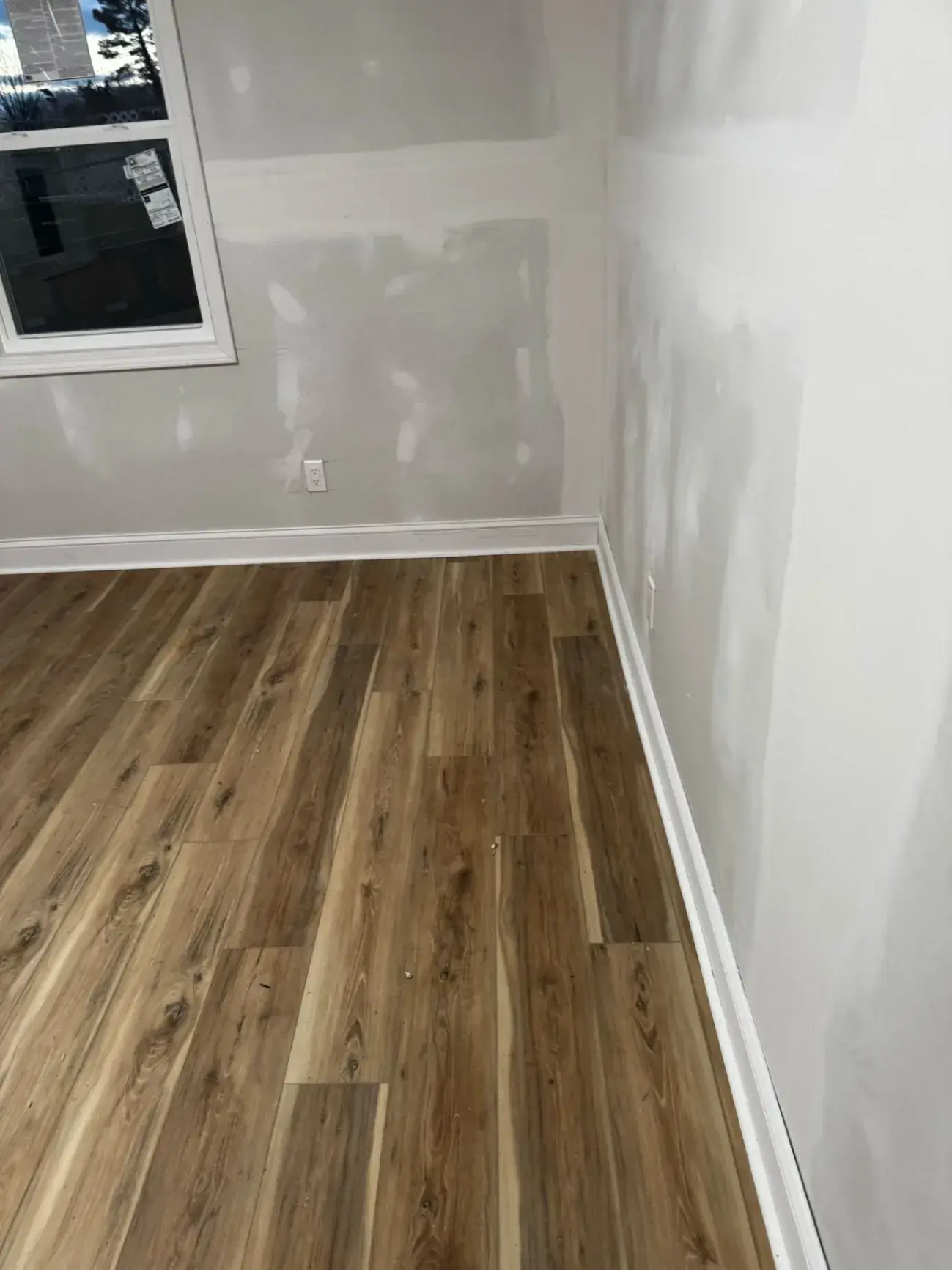 Warm wood-look plank floor running along a white baseboard