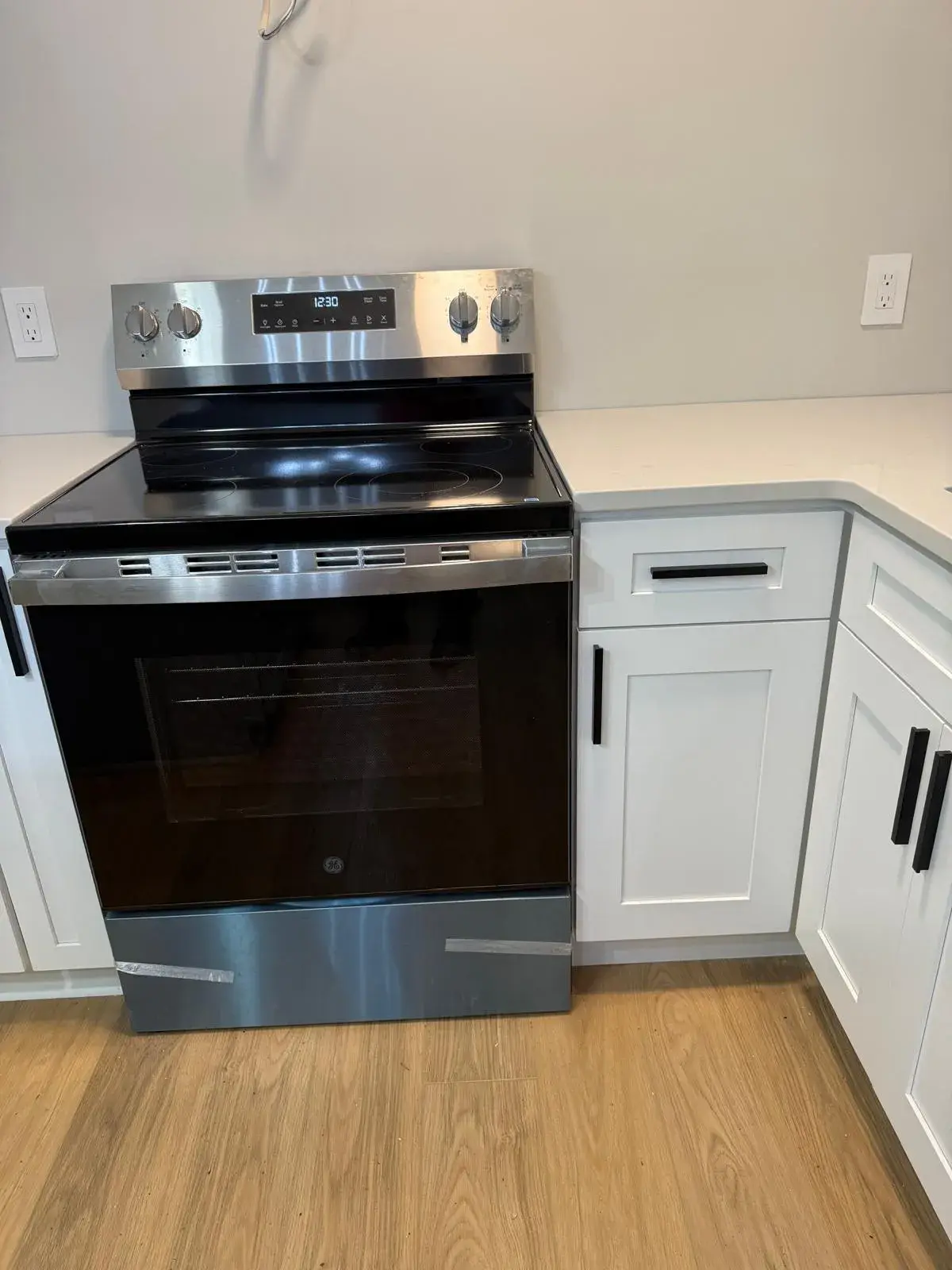 New stainless range between white cabinets with black pulls