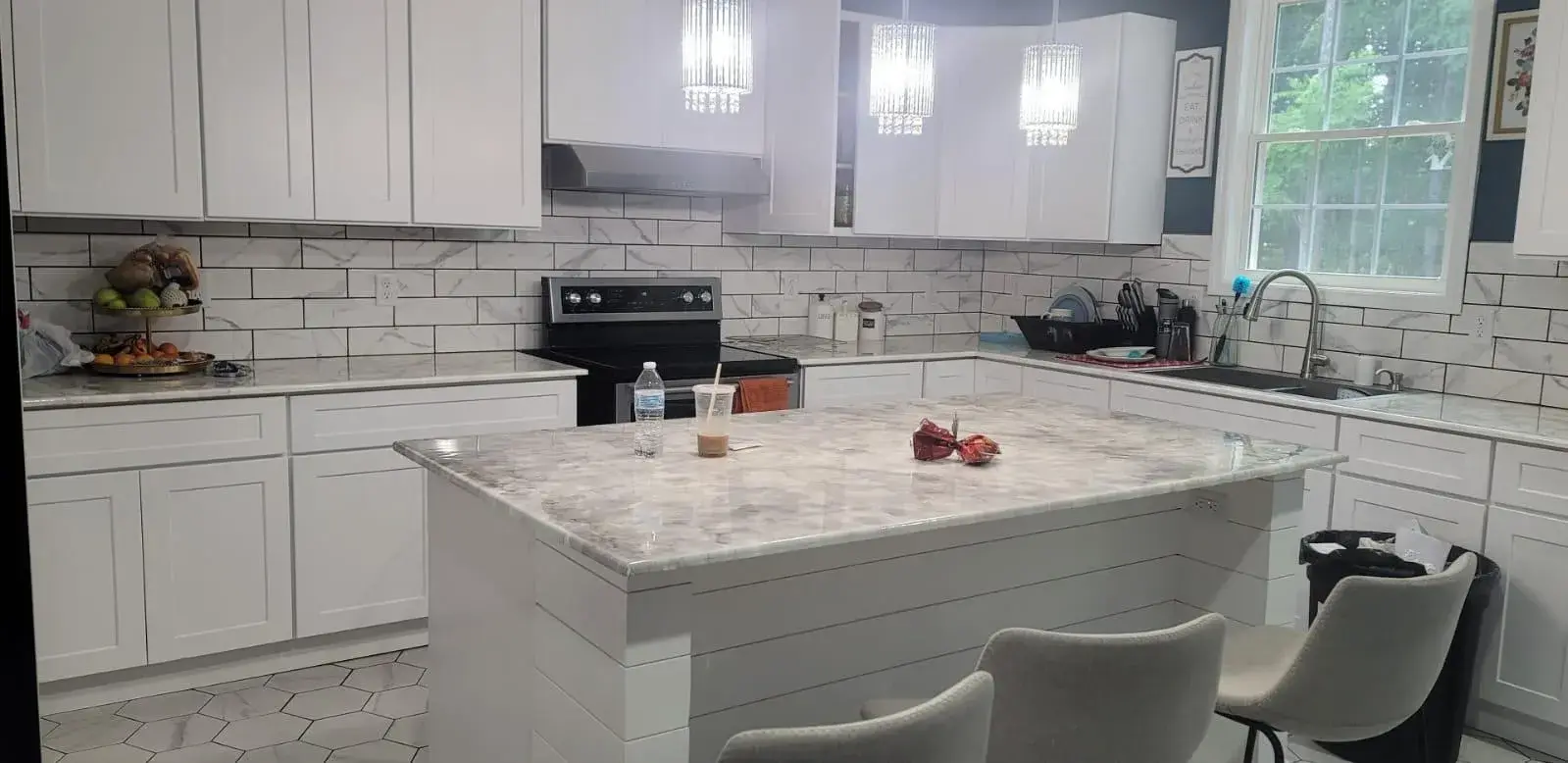 Kitchen island with a marble-look top, shiplap base and crystal pendant lights