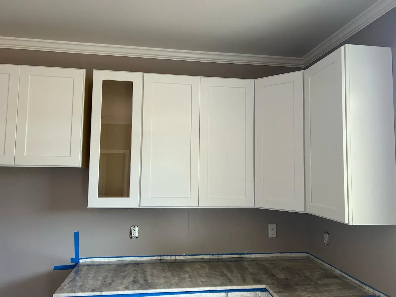 New white wall cabinets with a glass-front door during installation