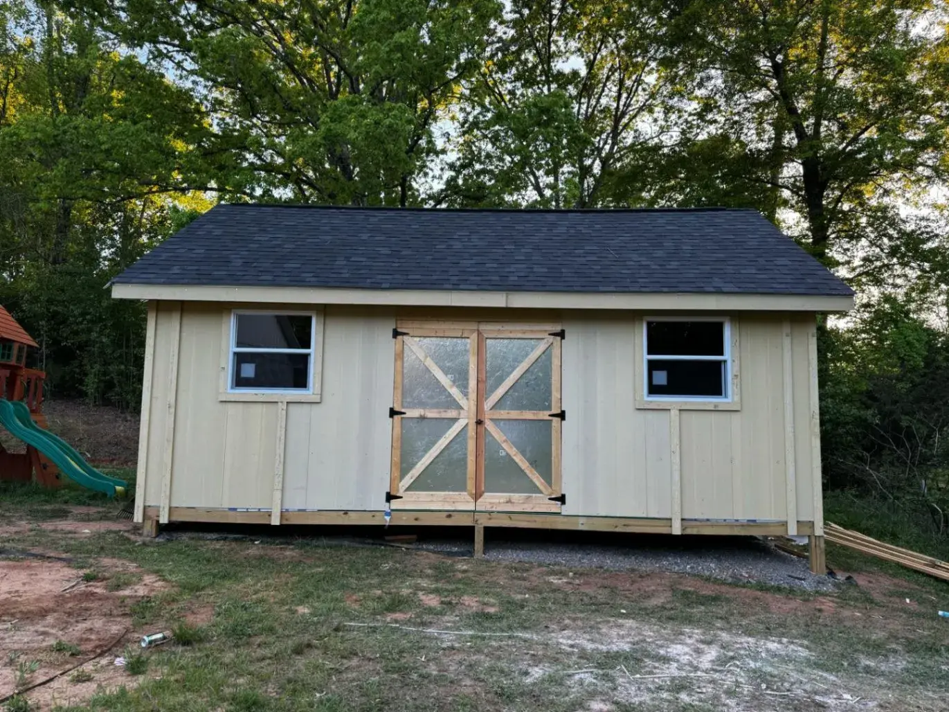 Finished cream shed with double doors and a dark shingle roof