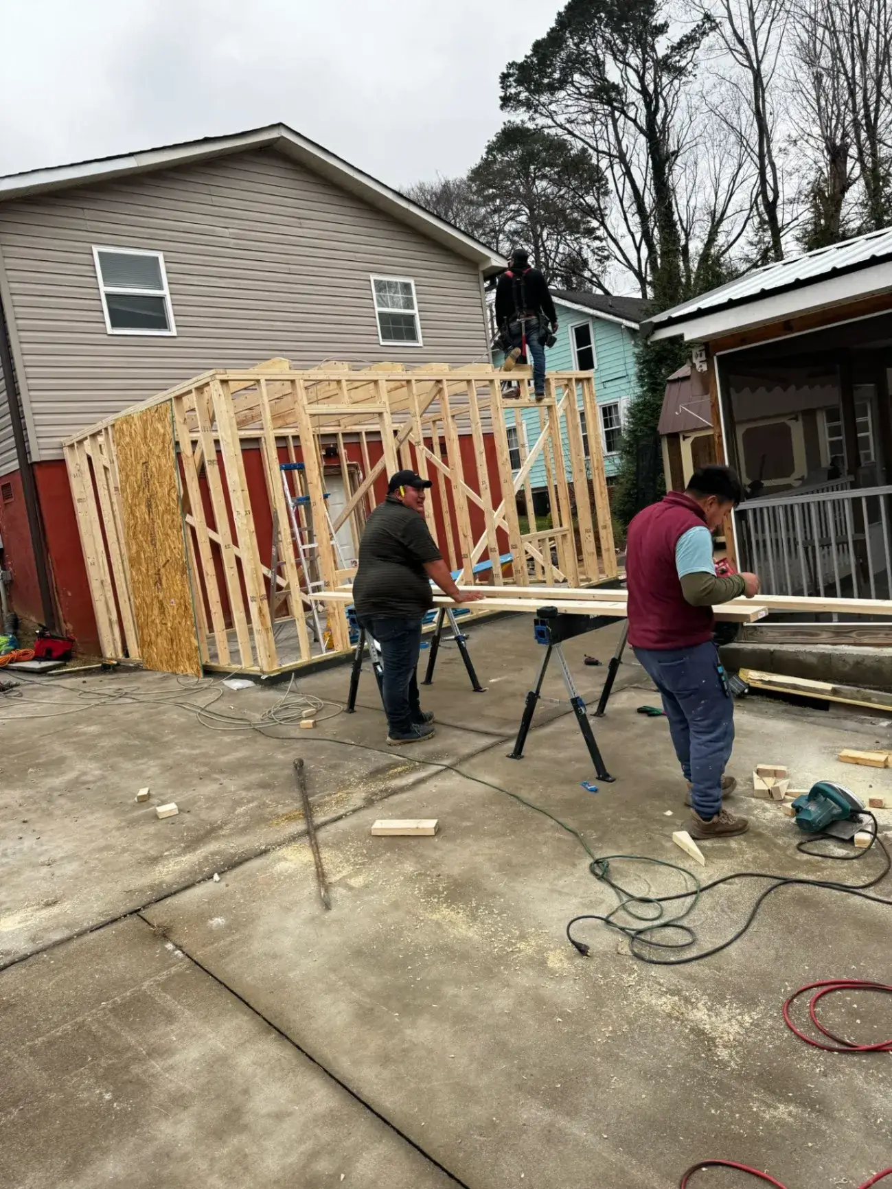 Two Kava crew members cutting lumber at a framing job