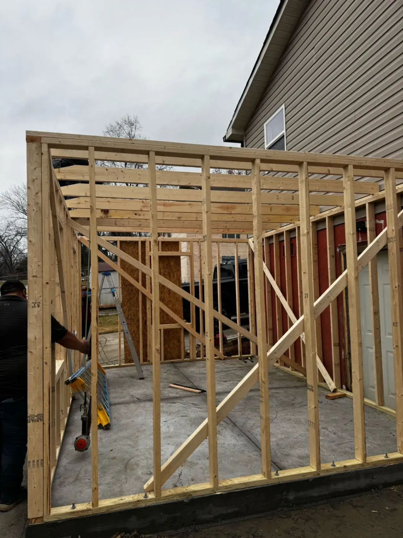 Wall framing standing on a concrete slab beside a home