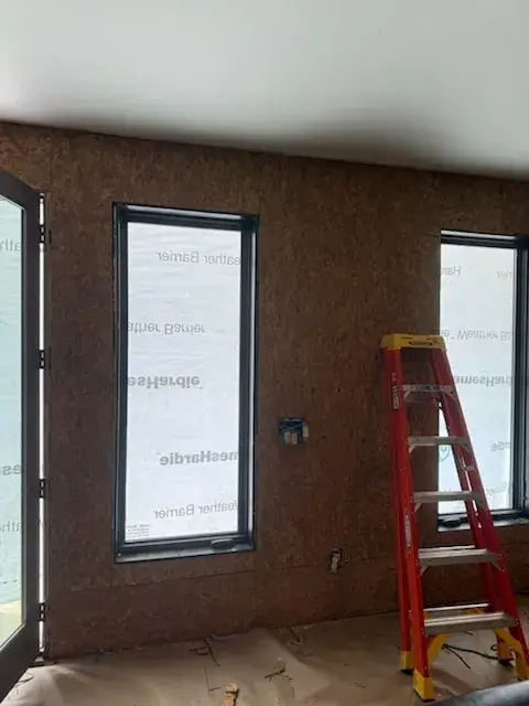 Tall black windows and a ladder in a room during work